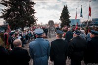 Zdjęcie kolorowe, przedstawiające służby mundurowe i zgromadzonych przed pomnikiem.