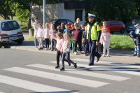 Zdjęcie kolorowe, przedstawiające policjanta ruchu drogowego i dzieci z klasy pierwszej.