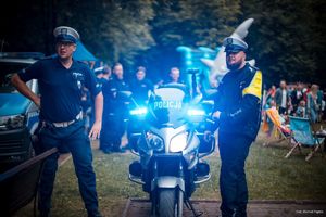 Zdjęcie przedstawiające policjantów, motocykl oraz dziecko na motocyklu.