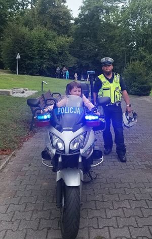Zdjęcie przedstawiające dziecko na motocyklu oraz policjanta.