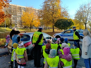 Zdjęcie przedstawiające policjantów ruchu drogowego oraz dzieci kontrolujące samochód.
