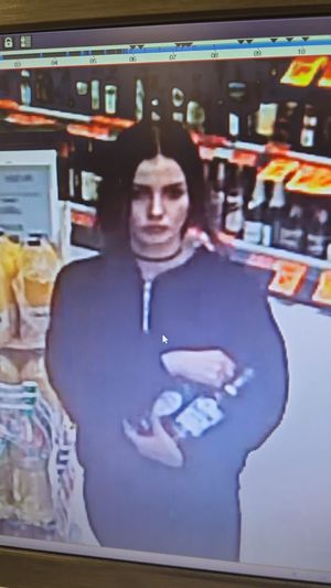 Zdjęcie podejrzanej kobiety trzymającej butelki alkoholu.