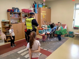 Zdjęcie policjanta ruchu drogowego oraz przedszkolaków w trakcie zabawy.