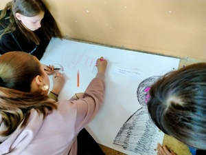 Zdjęcie przedstawiające dzieci w trakcie rysowania plakatu.